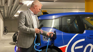 Ein Mann lädt ein Elektroauto mit einer Wallbox in einer Tiefgarage.