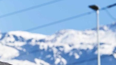 Ein Mann mit Brille steht vor einem Bergpanorama.